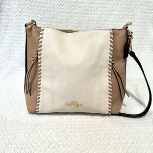 A coach cream colored black and gold crossbody bag